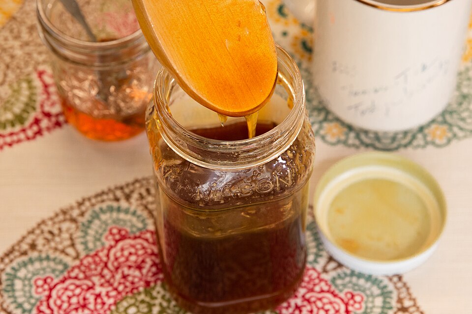 Golden HOC organic honey poured into a glass jar